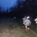 Several runners run down the trail in the first mile of the race before the sun comes up.